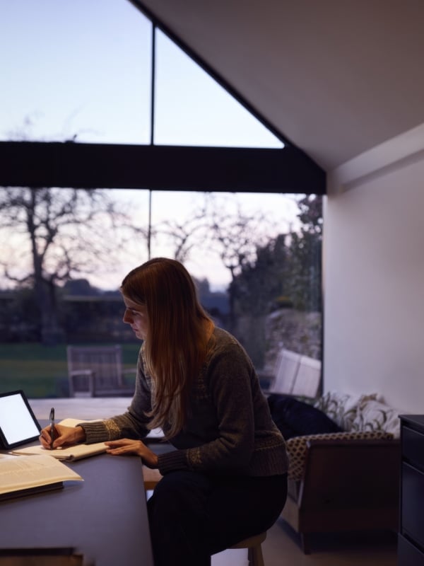 woman in dark room sitting at table with laptop